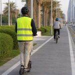 An electric scooter rider wearing a helmet and safety vest on a designated track in Doha Qatar